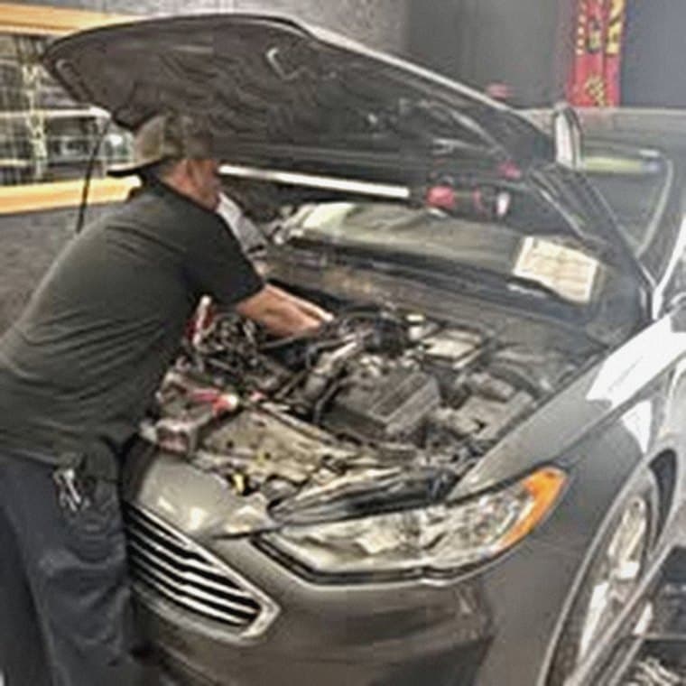 A Picazo's Garage technician leaning into the engine bay of a Ford Fusion